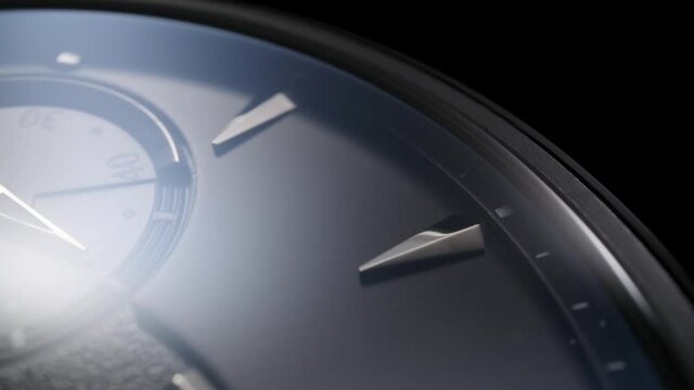 Little stopwatch second arrow on chronograph is running on rotating black swiss watch clockface with shiny metallic details and ceramic body. Closeup macro view 