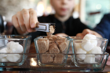 Child taking piece of sugar with tongs
