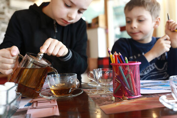 Child pouring tea in cafe