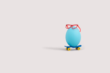 Creative funny concept with blue egg wearing sunglasses and riding skateboard