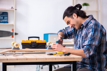 Young man repairing skateboard at workshop