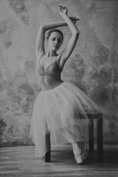 Young and graceful ballerina in pointe shoes and a tutu dances in the studio. Choreography and dancing classes concept. Creative ideas of ballet posing, performance. Black and white photo. 