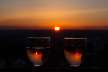 Two glasses with white wine on sunset background, evening sun is reflected in a misted glass. Concept of celebration, romantic date cocktail, love date, wine tasting