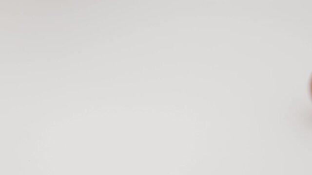 Chicken egg rotates on a white background. Close-up of an egg. Egg are rolling on the white table. Easter eggs background.