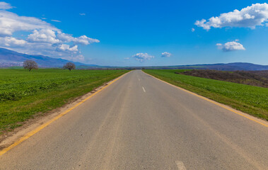 Asphalt road between green fields