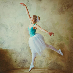 Young and graceful ballerina in pointe shoes and a tutu dances in the studio. Choreography and dancing classes concept. Creative ideas of ballet posing, performance. 