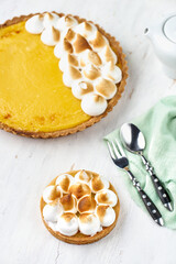 Tart with lemon curd with merenga decor on a light wooden background.