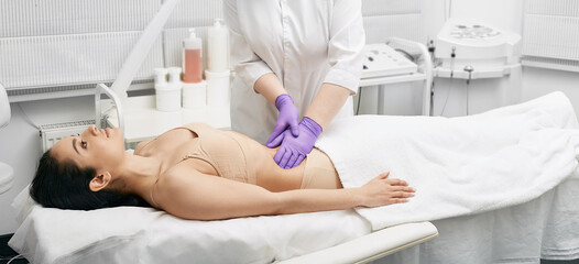 Doctor palpates a young woman's belly in a medical clinic. Physician doing a medical examination for female body for disease prevention