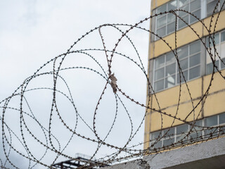 Close-up of the barbed wire on the fence. Building in the background. The concept of protecting...