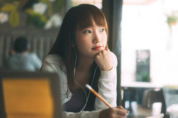 Young adult asian college student woman using laptop study and work online at cafe.