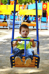 Fototapeta na wymiar Happy family concept. Little cheerful boy playing in the park, playground and laughing on a spring walk on a sunny day. Family holiday and togetherness, selective focus. 