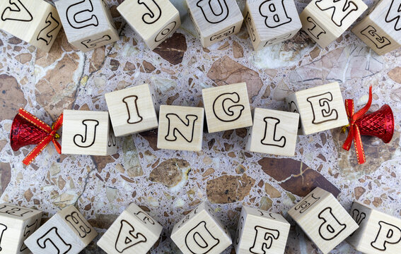 Jingle Bells Christmas concept with colorful red Xmas decorations and alphabet letters on wooden cubes over a stone background for the holiday season