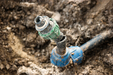 Repair and fixing concept. Broken plastic water pipe in back yard ditch