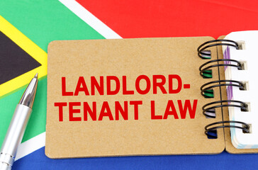 Against the background of the flag of South Africa lies a notebook with the inscription - LANDLORD-TENANT LAW