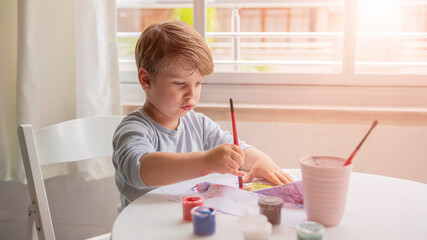 a child boy draws with paints