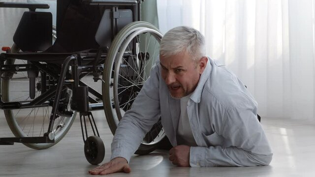 Disabled Senior Man Lying Near Wheelchair Calling For Help Indoor