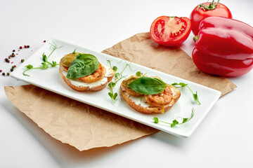 Appetizing Italian antipasti - bruschetta with shrimp, basil and avocado mousse, served on a white plate on a white plate