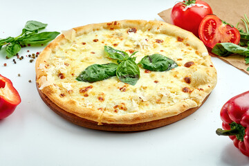 Italian pizza with cheese and basil on a white plate, in a composition with vegetables. Classic pizza 4 cheese. shallow depth of focus