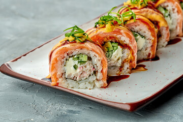 Delicious sushi Philadelphia roll with cream cheese, avocado, salmon in a white plate on a gray background. Japanese food. shallow depth of focus