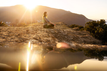 woman meditating in lotus pose at sunrise