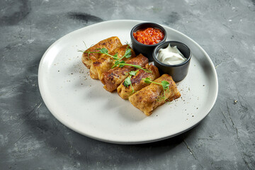 Appetizing Ukrainian blini with grounded meat filling, served in a white plate on a grey background. Flatjack pancake
