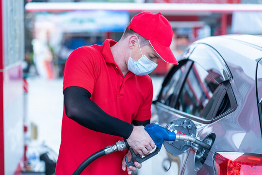 Man Wearing A Mask To Prevent COVID 19 Pick Up The Dispenser From The Oil Pump And Fill The Car With Gas At The Gas Station