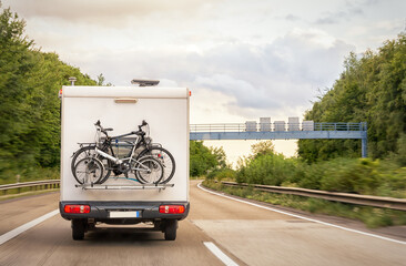 A camper with a cycle carrier attached to the rear with two bicycles is driving on the Autobahn....
