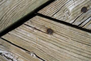 Close up macro view looking straight down on three weather wooden planks with rusty nails. 
