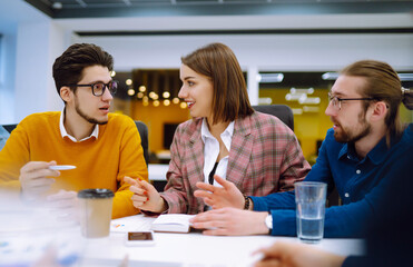 Group of young modern people working on project together. Business colleagues discuss financial...