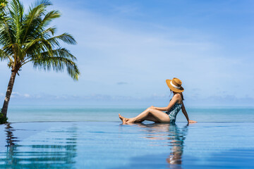 Young woman traveler relaxing and enjoying by a tropical resort pool while traveling for summer vacation, Travel concept