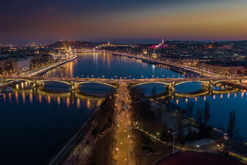 Budapest, Hungary - Aerial skyline panoramic view of illuminated Margaret Bridge at dusk. Parliament of Hungary, Szechenyi Chain Bridge and Buda Castle at background with clear golden and blue sky