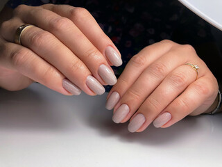 The work of a manicure master. Hands of a beautiful young woman and modern design.