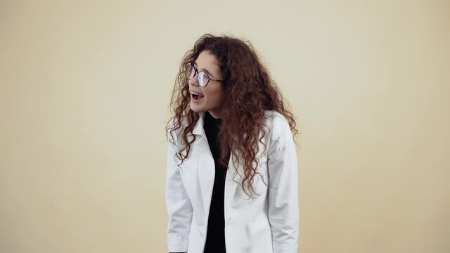 Cute young woman with curly hair, with a watery mouth, she glances at the room, smiling slowly. Young hipster in gray jacket and white shirt,