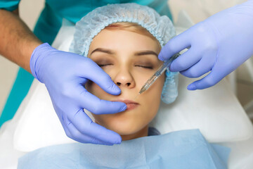 Close up cosmetologist hands in gloves introducing Hyaluronic acid in patient lips with perfect skin.