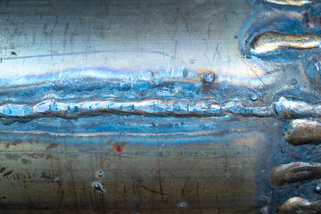 A piece of grunge rusty steel pipe with horizontal welds lines and traces. Aged vintage steampunk shiny piece od metal with scratches, stains from welding.
