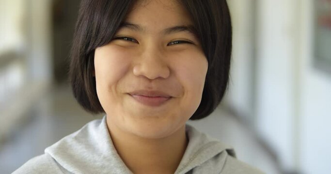 Slow motion scene of a cute young Asian teenage high school student girl is laughing happily and shyly.