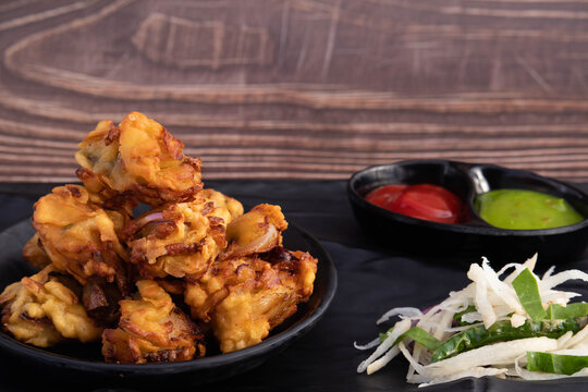Onion Pakoda Also Known As Kanda Bhajji, Pyaj Ke Pakode, Pakoda, Pyaaj Pakore, Pakora, Pyaaz Bajji Is Enjoyed In Rainy Season Across North And South India. Served With Green Chutney And Ketchup Sauce