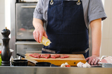 The chef of the restaurant pours meat with oil.