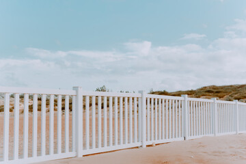 white fence on a sandy beach on a sunny summer day. Horizontal image