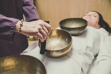 Soft focus view of a woman practicing holistic activities with Tibetan bells. Meditation and...