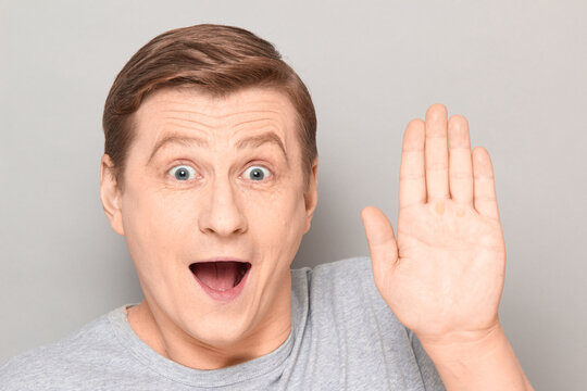 Portrait of happy overjoyed funny man raising hand and waving palm