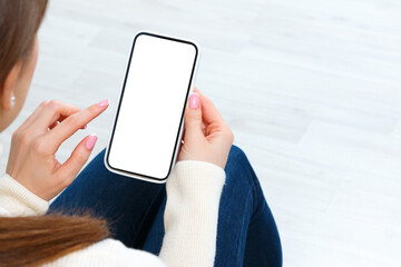 Back view of girl holding smartphone with white blank screen mockup. Lifestyle concept with digital technology.