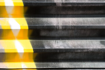 corrugated metal with black and yellow graffiti 