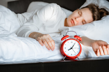 young woman sleeping comfortably on white cozy pillow. lazy single woman overslept work. Time to...
