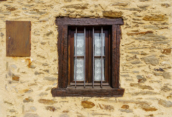 Fototapeta na wymiar Wooden window in old facade of stone house in bright colors.