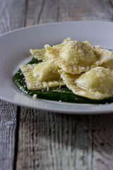 Ravioli stuffed with potatoes and carrots on a bed of borage puree with a sprinkling of Parmesan cheese and black pepper