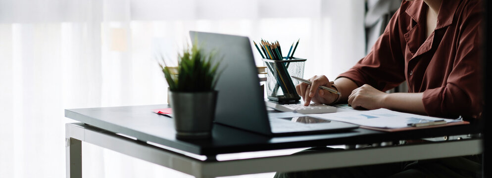 Business woman using calculator for do math finance on wooden desk in office, tax, accounting, statistics home accounring concept.