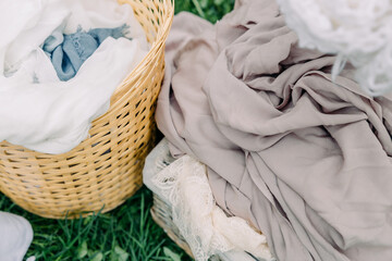 handmade wicker basket in rustic style with freshly washed linen. Drying and hanging clothes on clothespins in the garden.