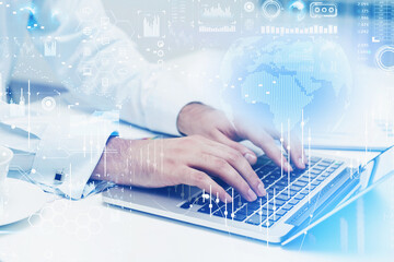 Businessman hands typing in laptop on table, graph changes and network icons. Globe projection above device.