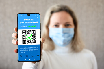 Woman shows smartphone with COVID-19 vaccine passport, vaccination and travel concept